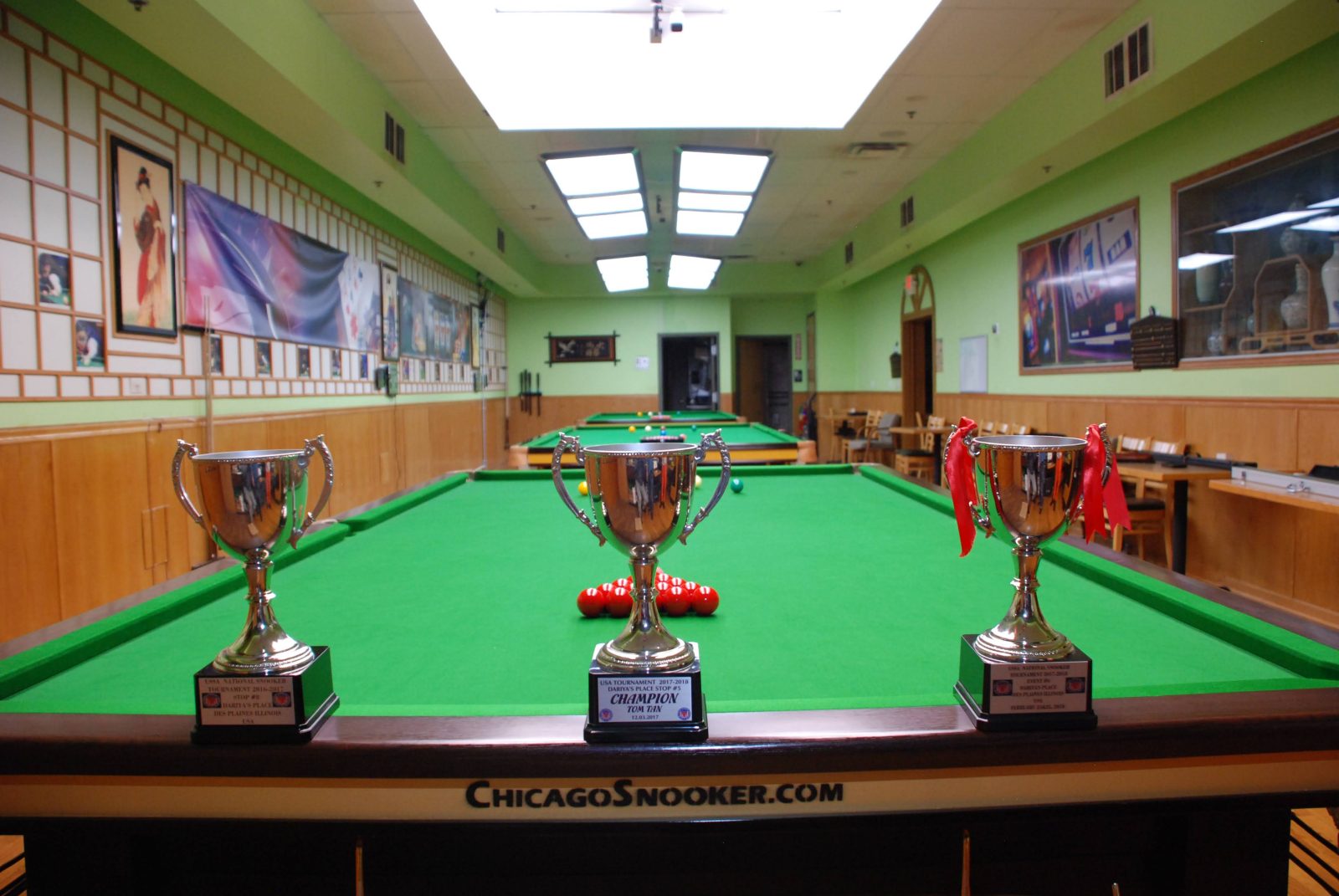 Chicago Snooker Club — tournament trophies on a match table, tables in play beyond